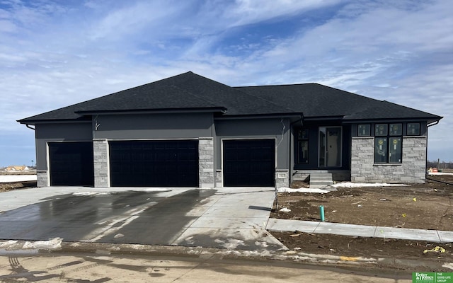 prairie-style house featuring an attached garage, stone siding, and concrete driveway