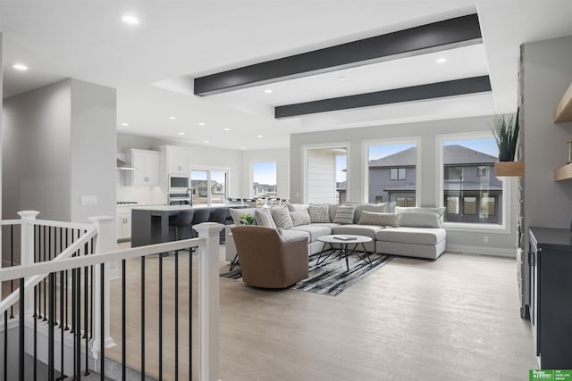 living room featuring baseboards, beamed ceiling, recessed lighting, and light wood-style floors