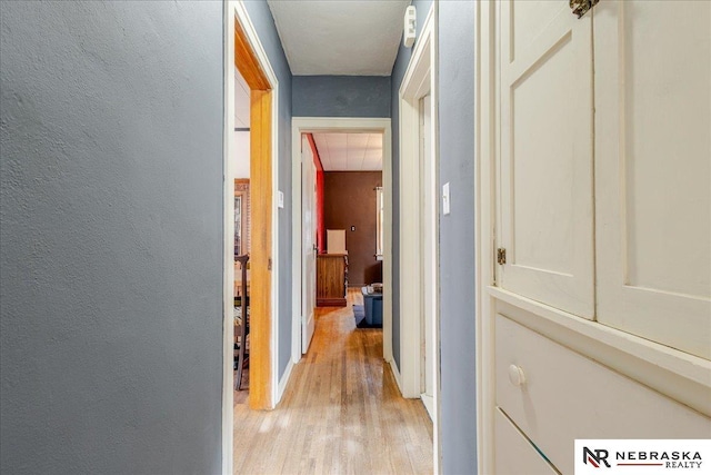 hall with light wood-style floors and a textured wall