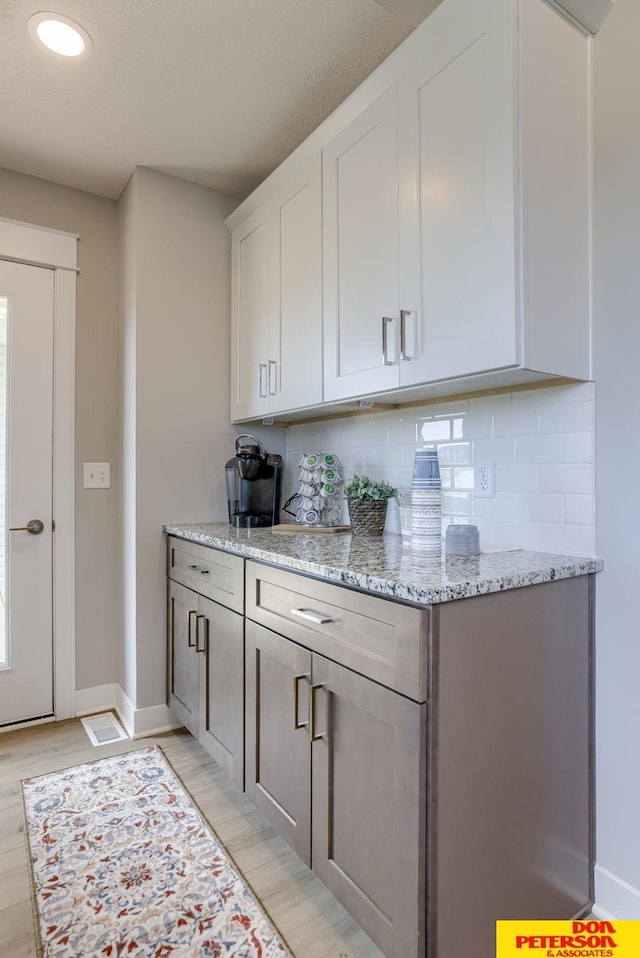 3563 Little Bluestem Rd, Fremont, NE 68025 - kitchen with backsplash, light stone countertops, light wood-type flooring, white cabinets, and recessed lighting