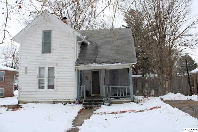 view of front facade with a shingled roof and a chimney