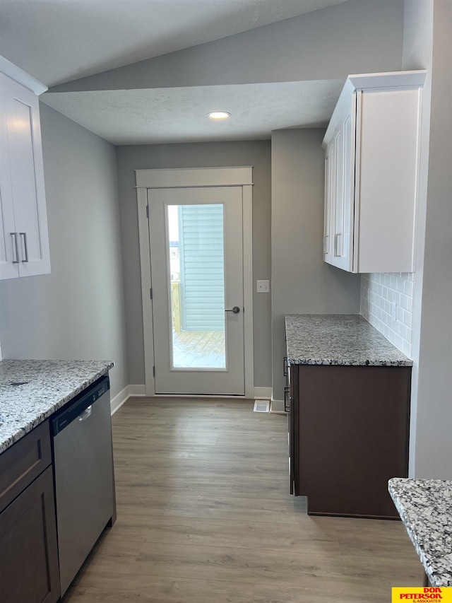 kitchen featuring light stone counters, light wood-style flooring, stainless steel dishwasher, white cabinetry, and dark brown cabinets