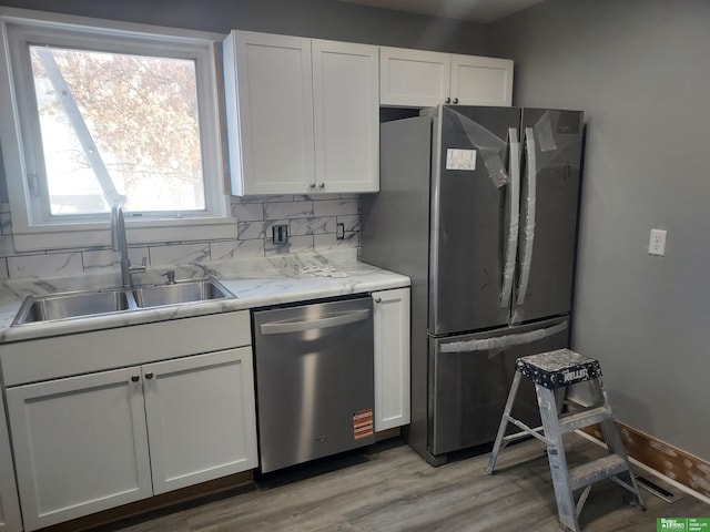 kitchen featuring stainless steel appliances, white cabinetry, a sink, and decorative backsplash