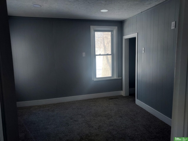 carpeted spare room featuring baseboards and a textured ceiling