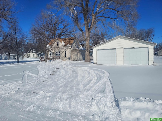 yard layered in snow featuring a garage and an outdoor structure