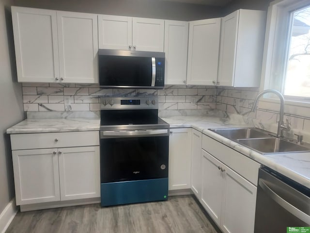 kitchen featuring decorative backsplash, appliances with stainless steel finishes, white cabinets, and a sink