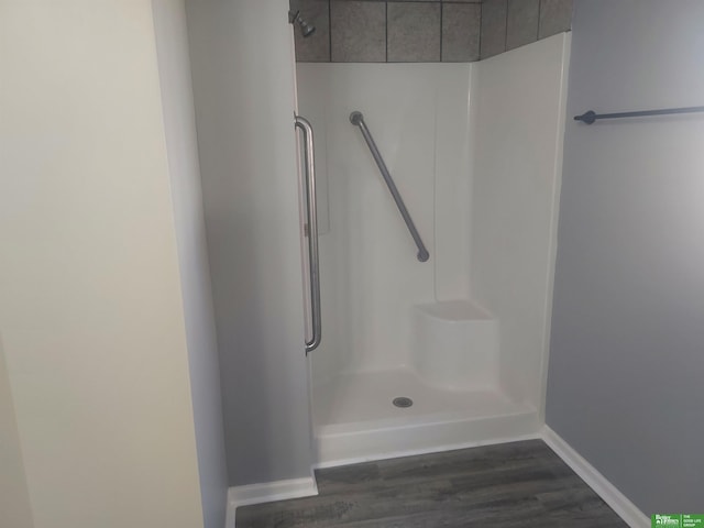 bathroom with a stall shower, baseboards, and wood finished floors