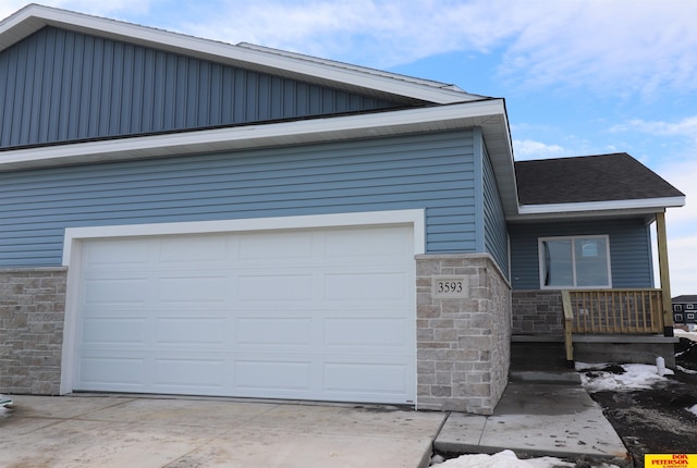 view of front of property featuring stone siding, roof with shingles, and concrete driveway