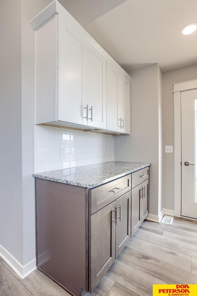 3593 Little Bluestem Rd, Fremont, NE 68025 - kitchen with light wood finished floors, decorative backsplash, light stone countertops, and white cabinets