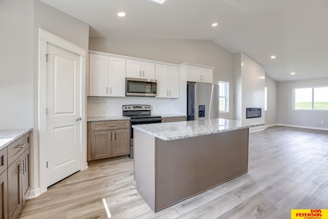 3593 Little Bluestem Rd, Fremont, NE 68025 - kitchen with stainless steel appliances, lofted ceiling, light wood-type flooring, a center island, and light stone countertops