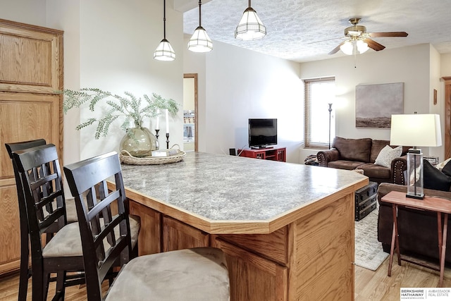 kitchen with a kitchen bar, light wood-style flooring, open floor plan, and a textured ceiling