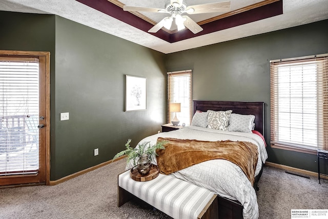 carpeted bedroom with a tray ceiling, visible vents, baseboards, and ceiling fan