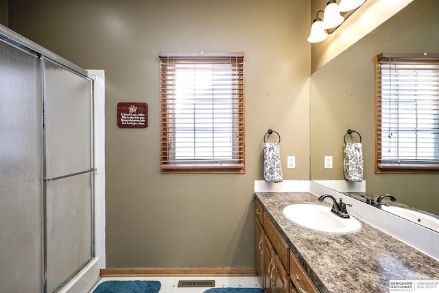 full bath with a shower with door, visible vents, baseboards, and vanity