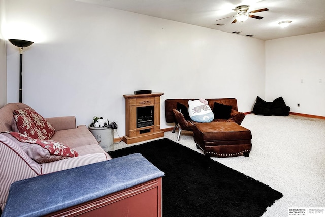 living room with a ceiling fan, visible vents, baseboards, a fireplace with raised hearth, and carpet flooring