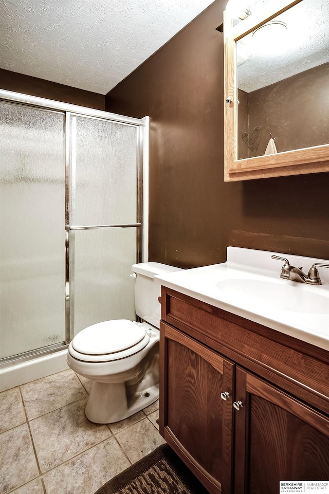 bathroom featuring a shower stall, a textured ceiling, vanity, and toilet