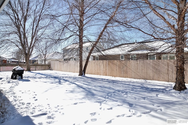 snowy yard featuring a fenced backyard