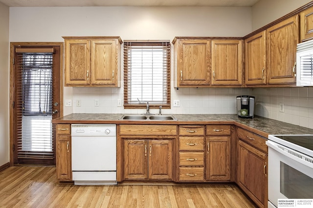 kitchen with light wood-style flooring, a sink, backsplash, white appliances, and brown cabinetry