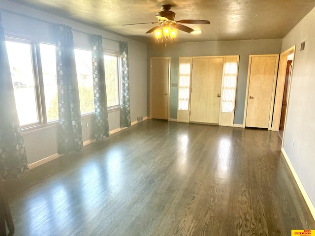 spare room featuring dark wood-style floors, visible vents, plenty of natural light, and baseboards