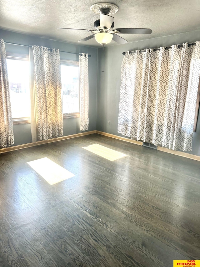 spare room featuring dark wood-type flooring, ceiling fan, a textured ceiling, and baseboards