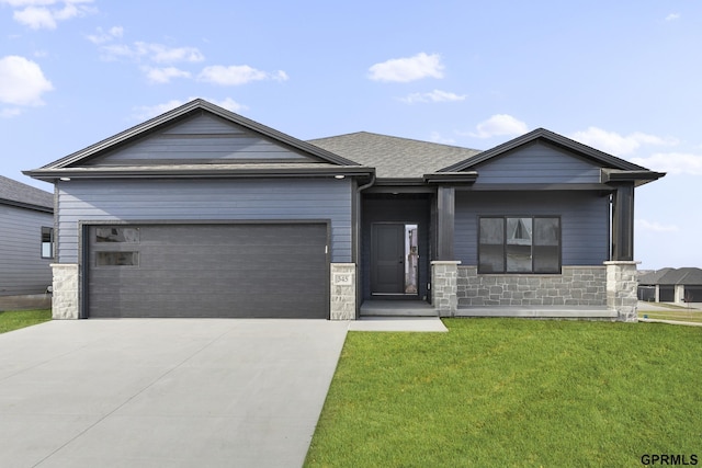 view of front of house featuring a garage, a shingled roof, stone siding, concrete driveway, and a front yard