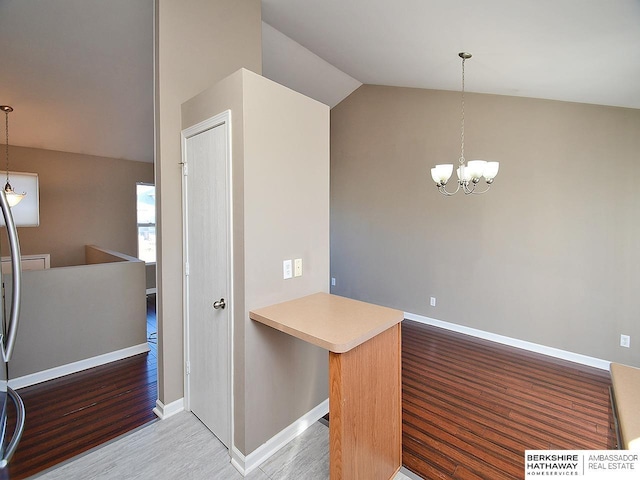 kitchen featuring pendant lighting, a notable chandelier, vaulted ceiling, and wood finished floors