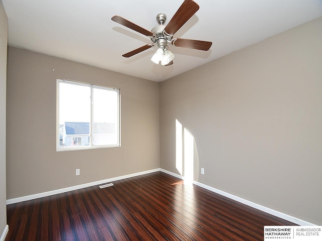 empty room featuring ceiling fan, dark wood finished floors, visible vents, and baseboards