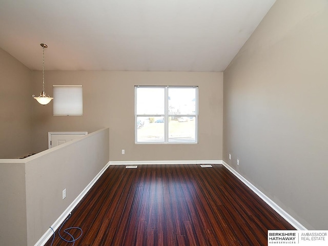 spare room featuring dark wood-type flooring, visible vents, and baseboards