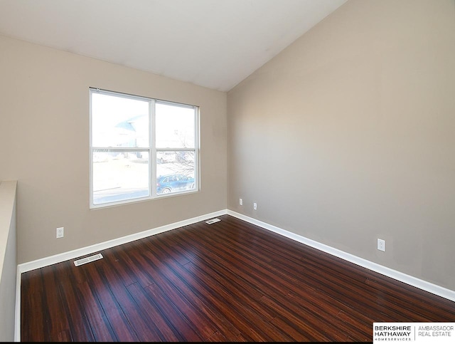 unfurnished room featuring lofted ceiling, visible vents, baseboards, and wood finished floors