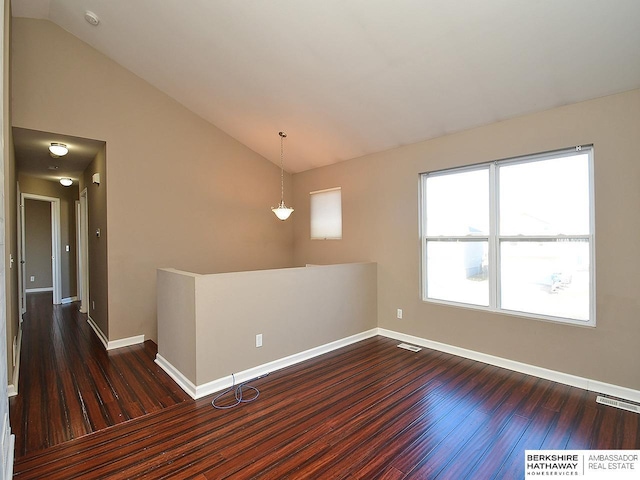 unfurnished room with vaulted ceiling, dark wood-style floors, visible vents, and baseboards