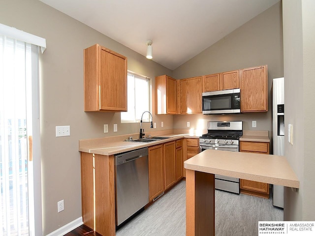 kitchen featuring lofted ceiling, light countertops, appliances with stainless steel finishes, a sink, and light wood-type flooring