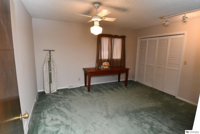 unfurnished bedroom featuring dark colored carpet, visible vents, ceiling fan, a textured ceiling, and baseboards