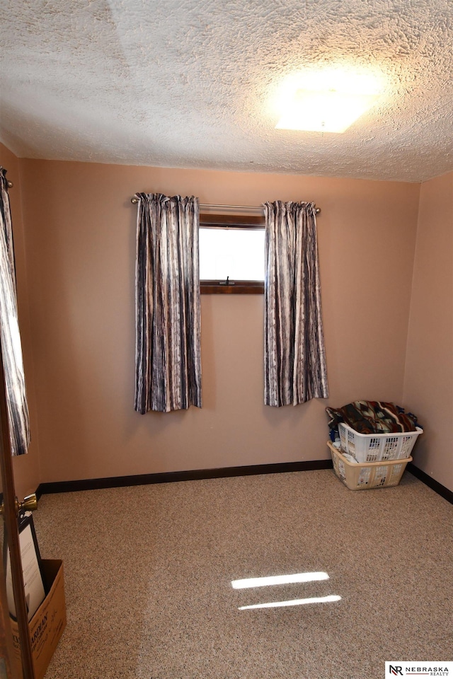 carpeted empty room with a textured ceiling and baseboards