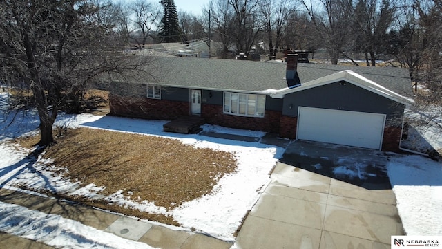 single story home with driveway, a shingled roof, a chimney, an attached garage, and brick siding