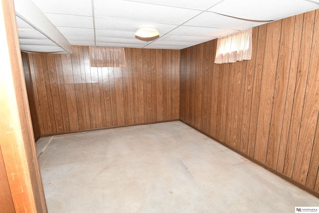 empty room featuring wooden walls and a drop ceiling