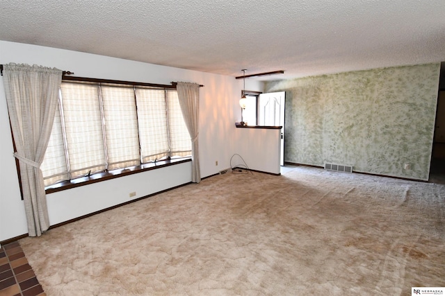 unfurnished room with baseboards, carpet, visible vents, and a textured ceiling