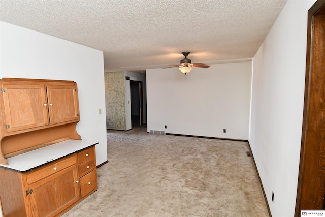 unfurnished room with baseboards, visible vents, light colored carpet, ceiling fan, and a textured ceiling