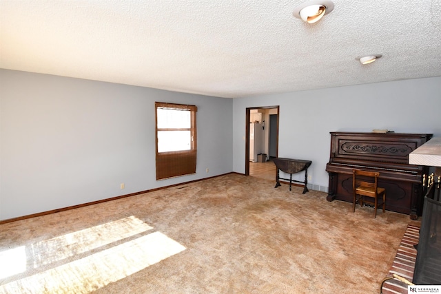 unfurnished room with light carpet, a textured ceiling, and baseboards