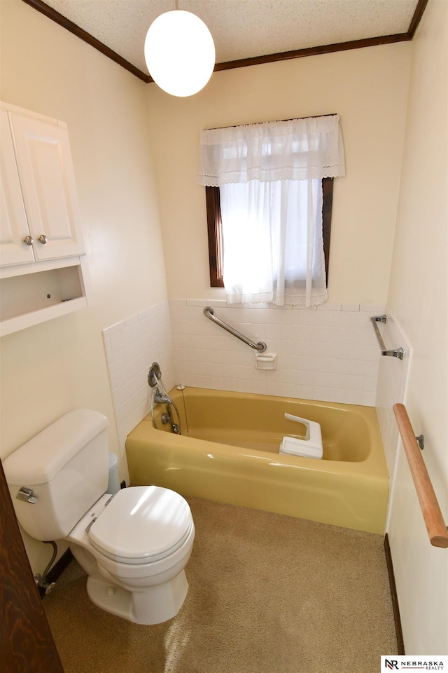 bathroom featuring ornamental molding, a textured ceiling, toilet, and a bath