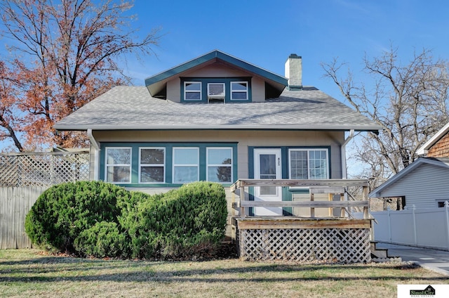 bungalow-style house featuring roof with shingles, fence, a chimney, and a front lawn