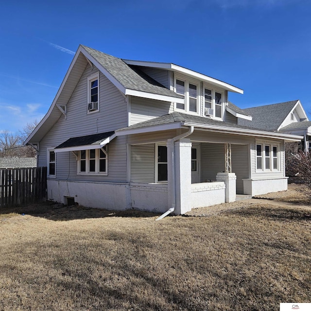 view of home's exterior featuring a shingled roof, fence, and a lawn