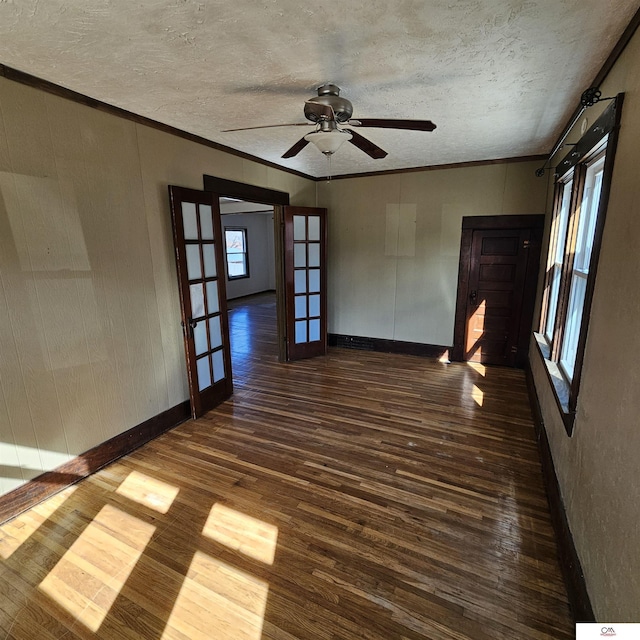 unfurnished room with baseboards, ornamental molding, dark wood-type flooring, a textured ceiling, and french doors