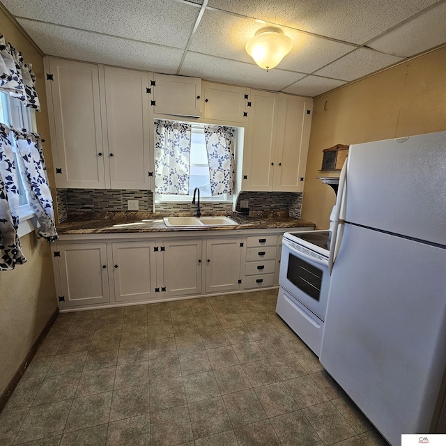 kitchen with white appliances, dark countertops, and white cabinets