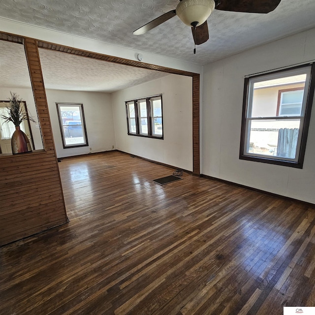 empty room featuring dark wood finished floors, a textured ceiling, baseboards, and ceiling fan