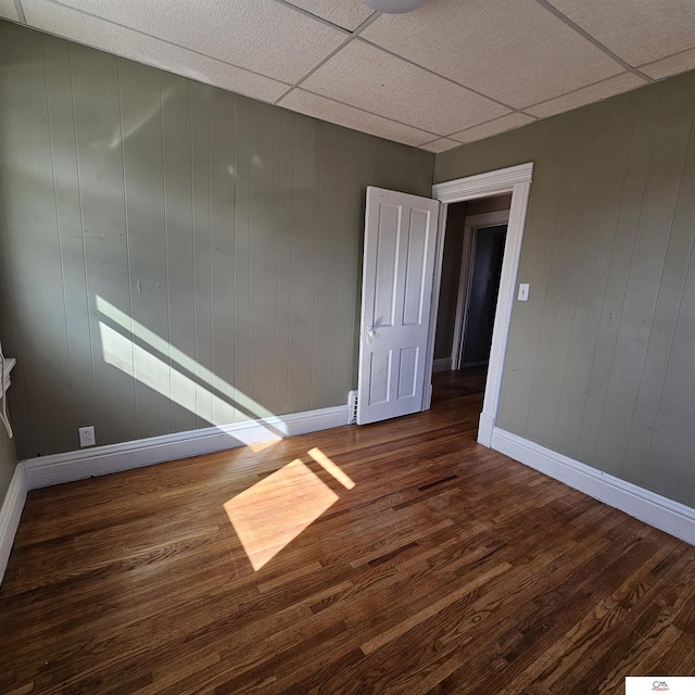 unfurnished room featuring a paneled ceiling, dark wood finished floors, and baseboards