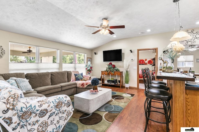 living room with a textured ceiling, vaulted ceiling, and wood finished floors