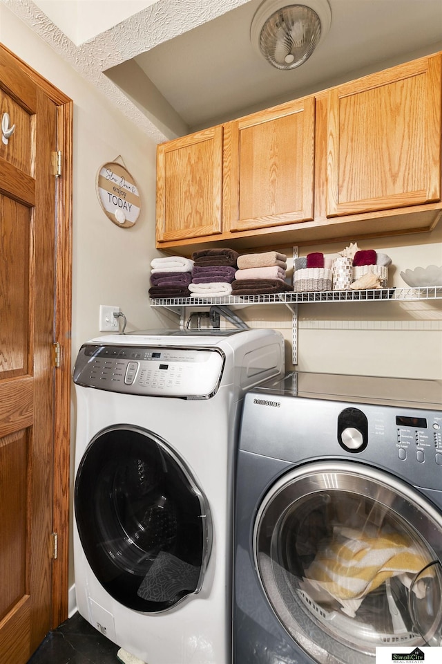 washroom featuring cabinet space and washing machine and clothes dryer