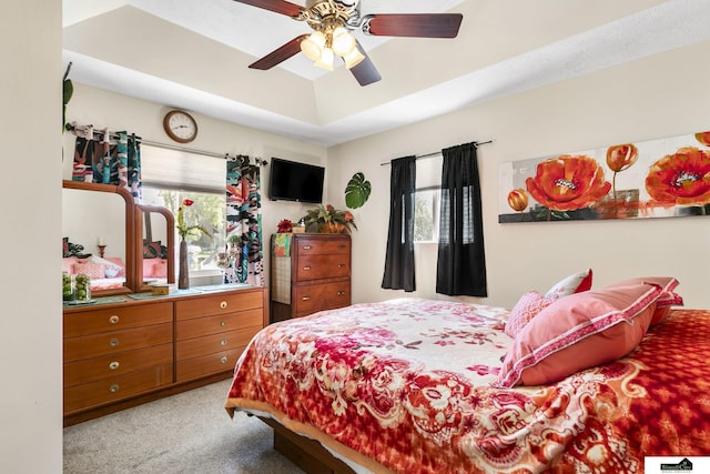 carpeted bedroom with a tray ceiling and a ceiling fan