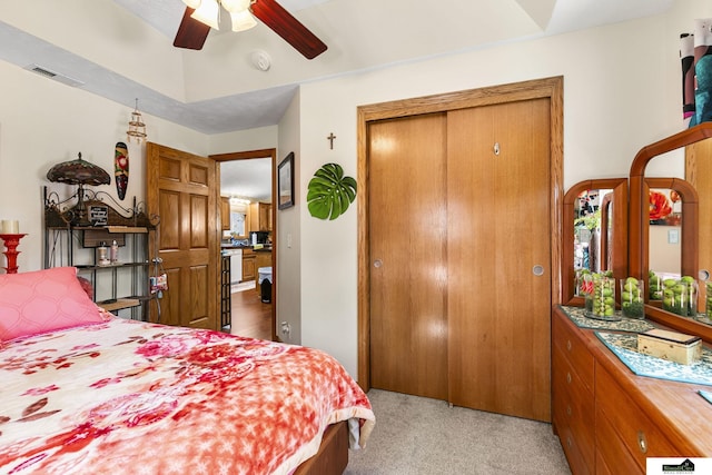 bedroom featuring visible vents, a closet, a ceiling fan, and light colored carpet