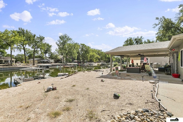 view of yard featuring a ceiling fan, a dock, and a water view