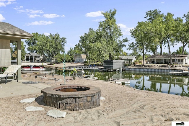 exterior space with an outdoor fire pit, a water view, and a dock